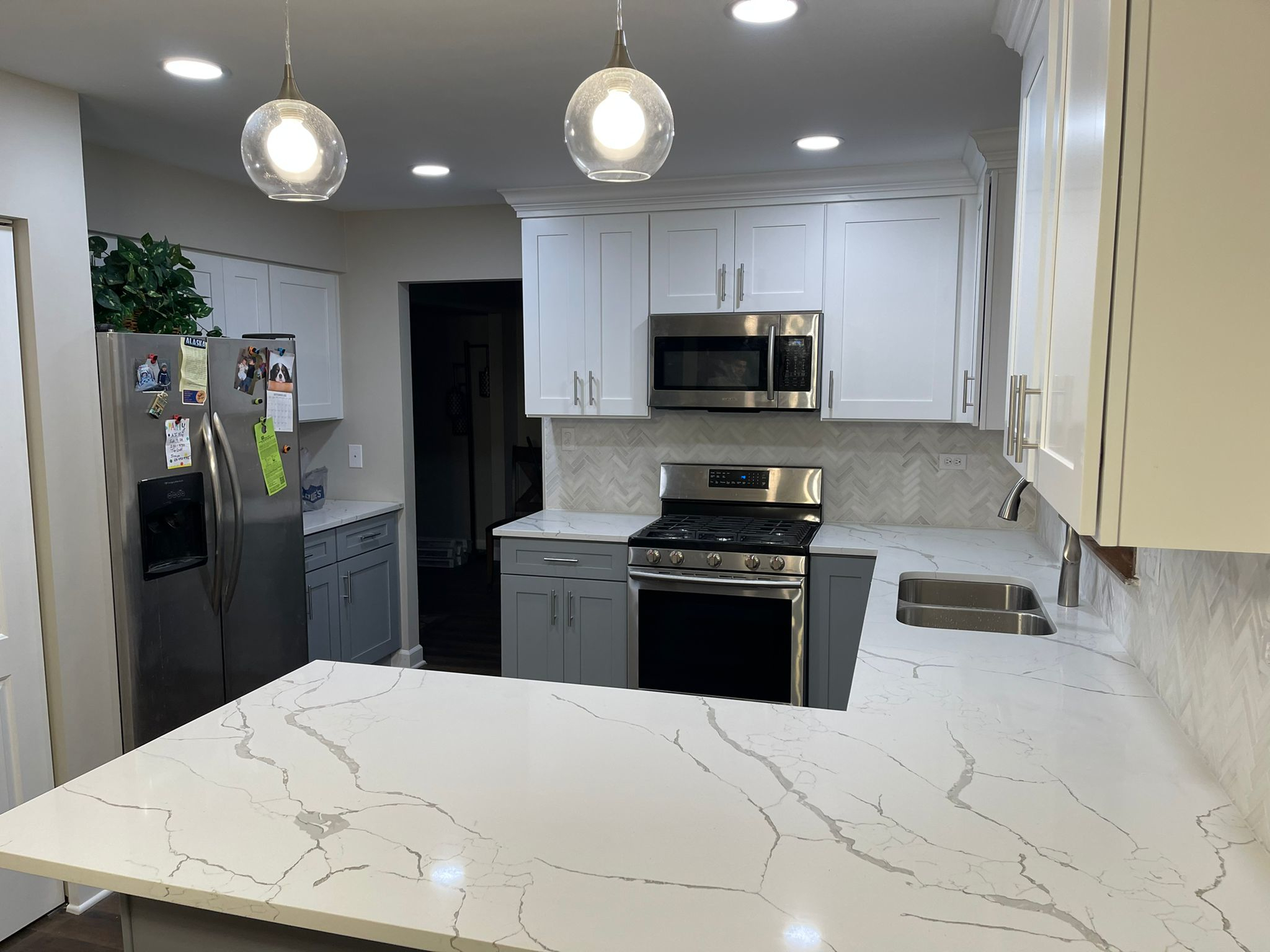 Completed kitchen renovation in Selkirk featuring two-tone cabinets, a large quartz island, and stainless steel appliances by JSDC Renovations.