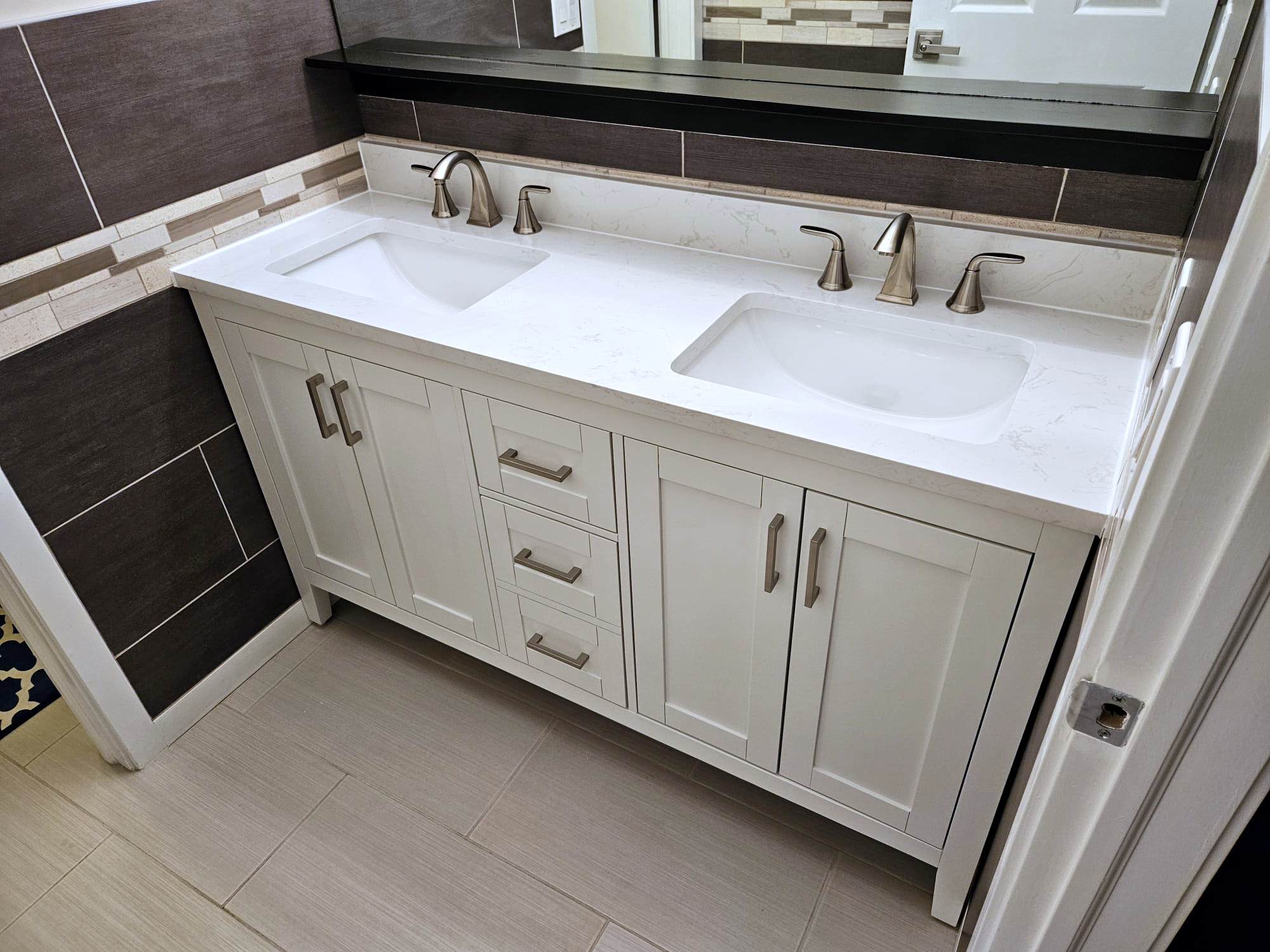 Custom bathroom renovation in East Selkirk featuring a white double vanity with a quartz top and modern tile backsplash.
