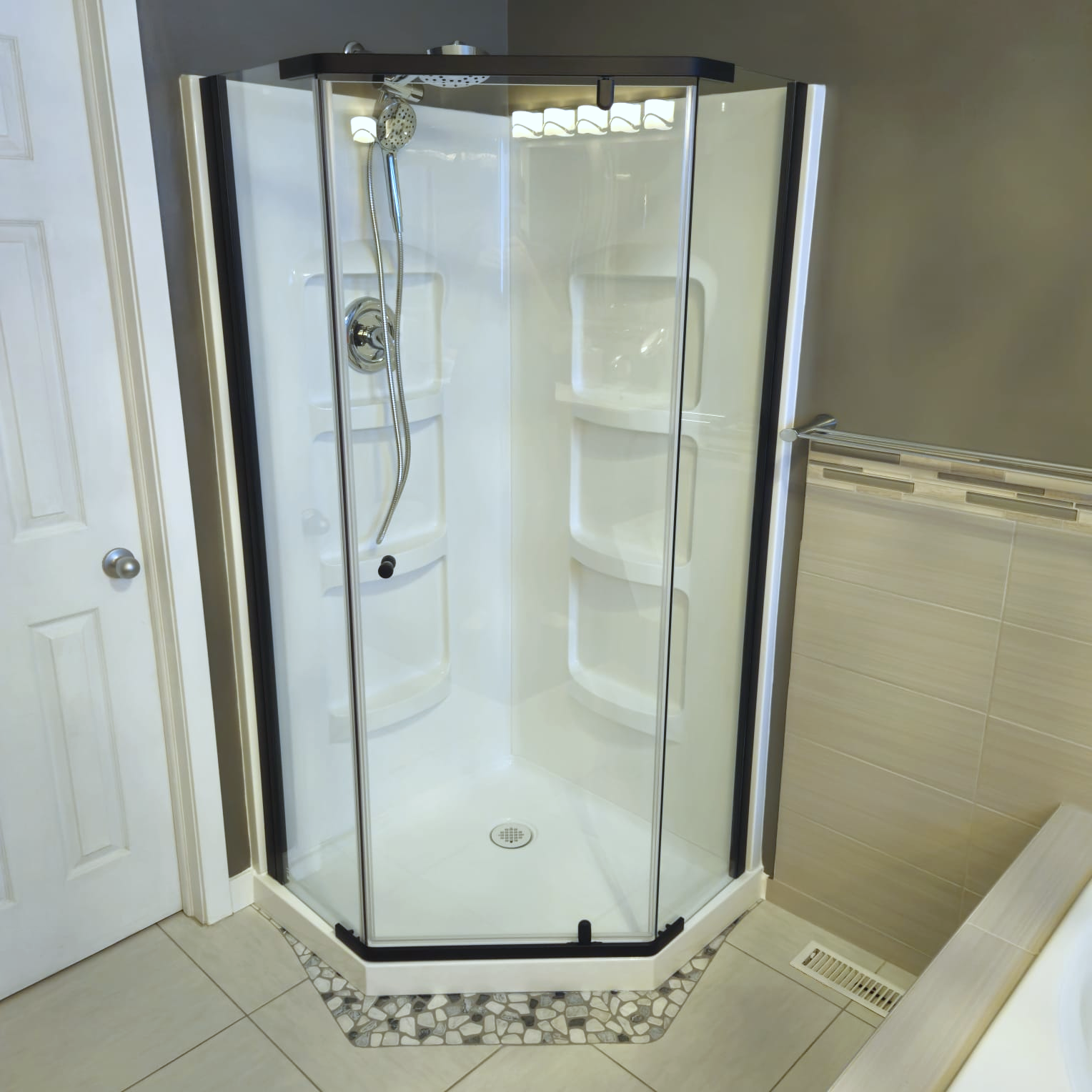 Corner shower installation for a bathroom renovation in Selkirk, featuring a black-framed neo-angle unit and custom pebble tile floor detail.