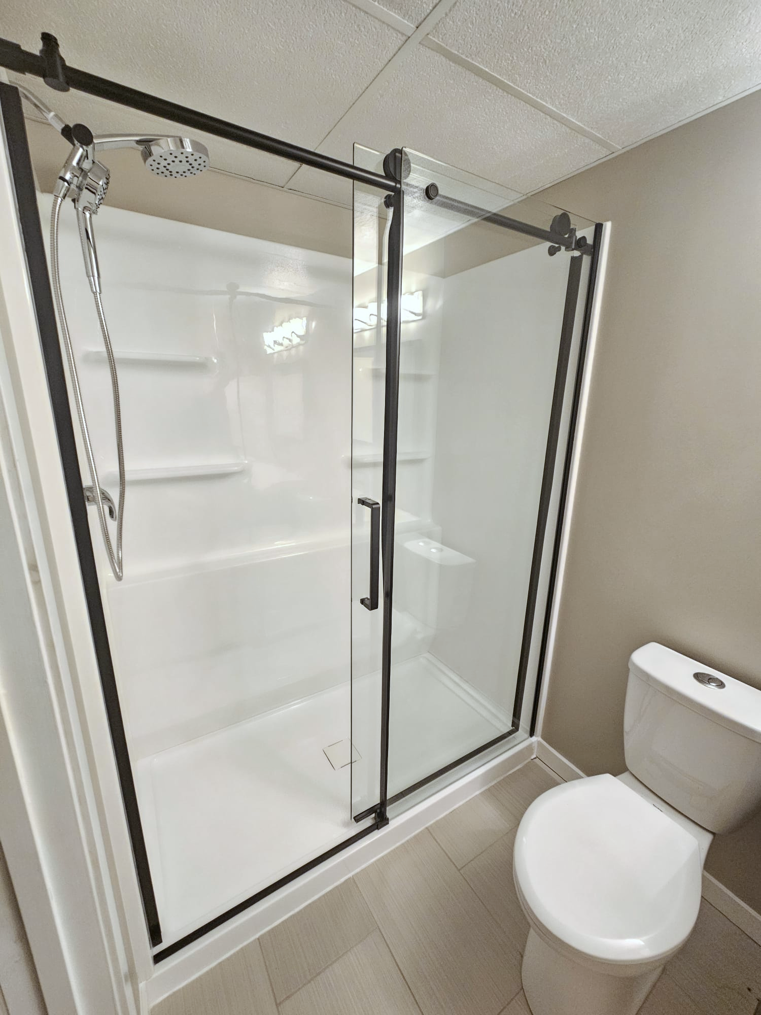 Professional shower installation as part of a bathroom remodel in Selkirk, featuring a modern black-framed sliding door and a low-maintenance acrylic surround.